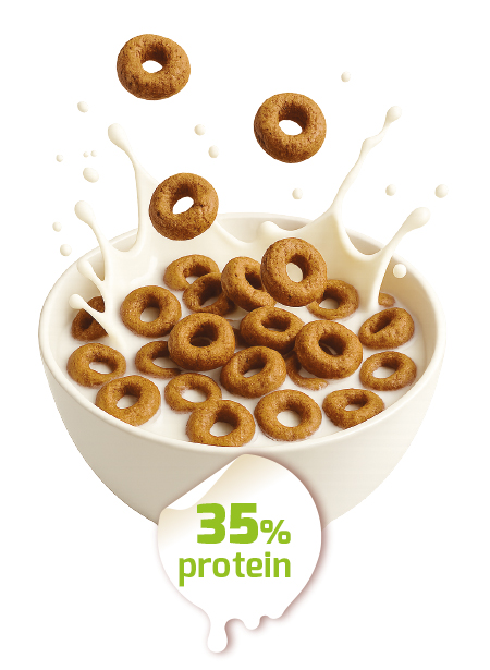 HALOS Protein Rings al cacao e nocciola Cereali a forma di anello HALOS immersi in una ciotola di latte con schizzi bianchi e un'etichetta 35% proteine.